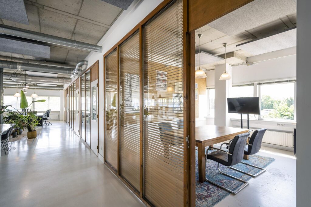 Modern kantoorinterieur aan de Anthony Fokkerweg met glazen vergaderruimtes, houten details en veel daglicht.